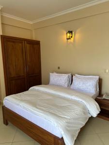 阿鲁沙Aves Executive Hotel的卧室配有一张带白色床单和枕头的大床。