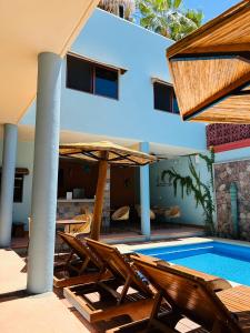 洛雷托Rosarito Hotel的一座带游泳池和椅子的度假村,毗邻一座建筑