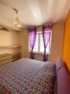斯佩隆加Villanna的一间卧室配有一张紫色窗帘的床