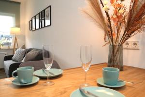 温特贝格Seeblick25 - Apartments - Balkony - WIFI - Great View - New & Modern的一张桌子,上面放着两杯酒,花瓶上放着鲜花