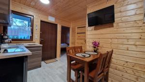 达布基Domki Sowia Polana的厨房配有桌子,木墙上配有电视。