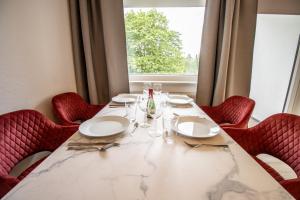 汉诺威Messe-Apartment für 5 Gäste mit Balkon und Lift的一张桌子、红色的椅子和大窗户