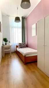 什切青Beautiful rooms in the center的一间卧室配有一张床和粉红色的墙壁