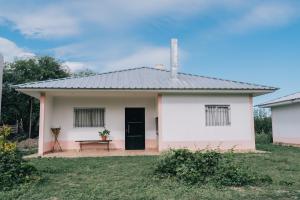 特尔马斯德里奥翁多Las Moras Del Manantial的一间白色的小房子,有黑色的门和长凳