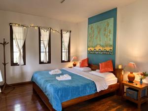 拜县Pairadise Hotel的一间卧室配有一张大床,配有蓝色床单和橙色枕头。