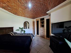 AtotonilcoRancho Labradores的一间带两张床、电视和砖砌天花板的卧室