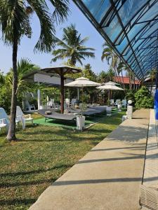 北碧Thai Garden​ Resort​ Kanchanaburi​的配有桌子、遮阳伞和椅子的度假村