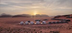 瓦迪拉姆rum guest house的一群在沙漠中的圆顶,伴随着日落
