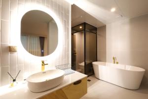 昌原市Changwon Denbasta Hotel Myeongseo的一间带水槽、浴缸和镜子的浴室