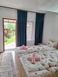 瓦杜伊泽Pensiunea Casa Ancuta的一间卧室设有两张床,里面饲养着粉红色的填充动物