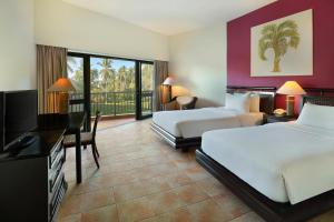 美娜多Manado Tateli Resort and Convention的酒店客房设有两张床、一张桌子和一台电视。