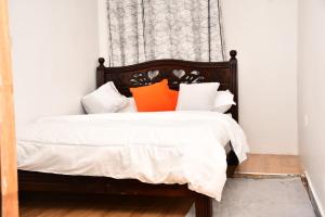 KisiiNyamira homes的一间卧室配有带橙色和白色枕头的床