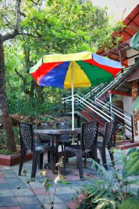 马迪凯里Katakeri Deluxe Holiday Homes的一张桌子和椅子,配有五颜六色的雨伞