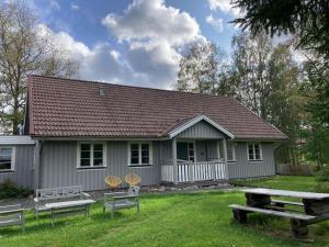 GunsjögårdenVilla Lägervik Vitsand的白色的小房子,配有野餐桌和椅子