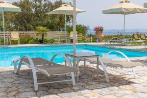 伊西翁Castello Antico Hotel的游泳池畔的一张桌子和两把椅子及遮阳伞