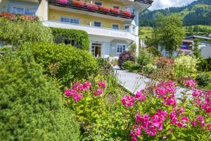 巴特霍夫加施泰因Hotel Garni Mühlbacher - inklusive kostenfreiem Eintritt in die Alpentherme的一座花园,在一座建筑前方种有粉红色花卉