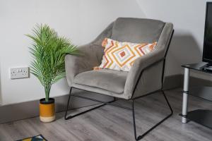 SheldonStylish apartment near NEC, Birmingham Airport, Resorts World, HS2, JLR的配有枕头和植物的灰色椅子