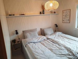 伦斯楚普Cozy Summer House In Lnstrup For 5 People,的一间卧室配有带白色床单和枕头的床。