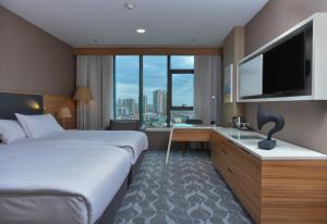 安卡拉DoubleTree by Hilton Ankara Incek的酒店客房配有一张床、一张书桌和一台电视。