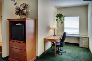 OkotoksLakeview Inns & Suites - Okotoks的酒店客房配有书桌、电视、书桌和椅子。
