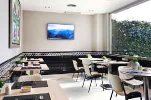 塞维利亚加泰罗尼亚希斯帕利斯酒店的餐厅设有桌椅和大窗户。