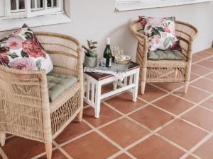 彼得马里茨堡Wylde Rose Cottage的两张柳条椅和一张带一瓶葡萄酒的桌子