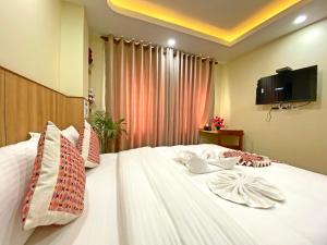 加德满都Hotel Lumbini Airport的卧室配有白色的床,墙上配有电视