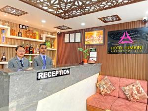 加德满都Hotel Lumbini Airport的两个男人站在酒店大堂的酒吧