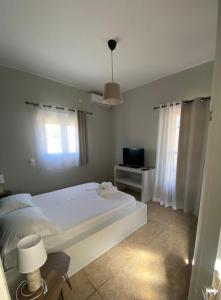 艾拉方索斯Okio - Μονοκατοικία δίπλα στη θάλασσα的卧室配有白色的床和电视。
