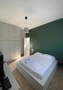艾拉方索斯Okio - Μονοκατοικία δίπλα στη θάλασσα的一间卧室设有一张白色大床和绿色的墙壁