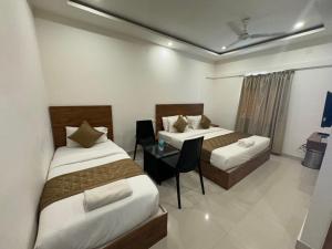班加罗尔Hotel Airport City的酒店客房设有两张床和一张桌子。