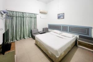 丹戎槟榔RedDoorz Syariah Near Pelabuhan Sri Bintan Pura Tanjungpinang的卧室配有一张白色大床和一把椅子