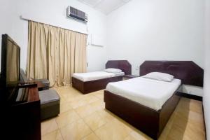 丹戎槟榔RedDoorz Syariah Near Pelabuhan Sri Bintan Pura Tanjungpinang的酒店客房设有两张床和电视。