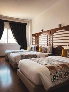 丹吉尔Hôtel Rembrandt的酒店客房设有三张床和窗户。