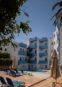 赫索尼索斯Simple Hotel Hersonissos Blue的游泳池旁的酒店拥有椅子和遮阳伞