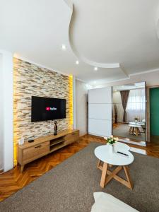 下米拉诺瓦茨Apartman Julija的一间客厅,在砖墙上配有电视