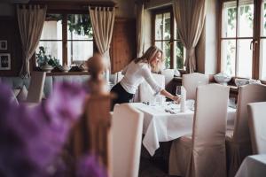 罗登戈Hotel Schönblick的女人在餐馆里摆桌子