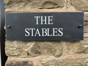 WortleyThe Coach House & The Stables Holiday Homes Windy Bank Hall Green Moor Yorkshire Peak District的石墙边的标志