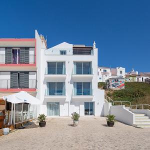 塞勒玛Residence Sol e Mar的海滩上的白色建筑,前面有植物