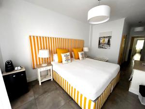 米尔芳提斯城Hotel HS Milfontes Beach - Duna Parque Group的一间卧室配有一张带橙色和白色条纹床头板的床