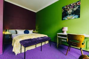 德累斯顿Boutique Hotel Rothenburger Hof的一间卧室设有绿色的墙壁和一张带紫色座椅的床