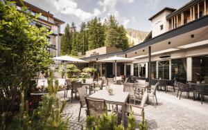 圣维吉利奥Excelsior Dolomites Life Resort的一个带桌椅和遮阳伞的户外庭院。