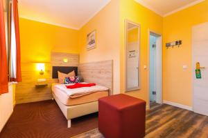 科瑟罗Hotel & Restaurant Hanse Kogge的卧室拥有黄色的墙壁,配有一张床和红色的凳子