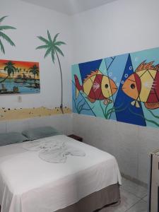 嘎林海斯港Pousada Porto Marola的一间设有一张床的客房,墙上挂有绘画作品