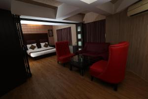 孟买Quaint Suites Hotel & Banquet的一间卧室,配有一张床和红色椅子