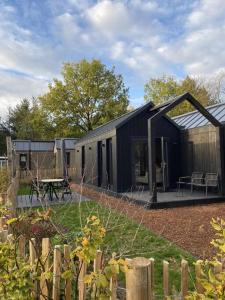 伊皮Knus I Tiny house op de Veluwe的一座黑色的建筑,在院子里设有野餐桌