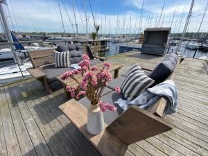 海利根港Hausboot Yara am Steg 1D的木制甲板配有沙发和鲜花桌