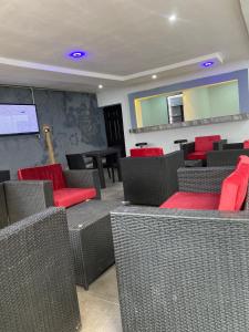 阿布贾lnfinity Luxury Apartment的一间设有红色椅子和投影屏幕的等候室
