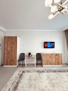 卡拉甘达Hotel Bereket Karaganda的客厅配有两把椅子、一张桌子和一台电视