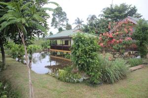 武吉拉旺LANDBOW GREEN VILLAGE Homestay Trekking & Village Tour的花园中水体旁的房子